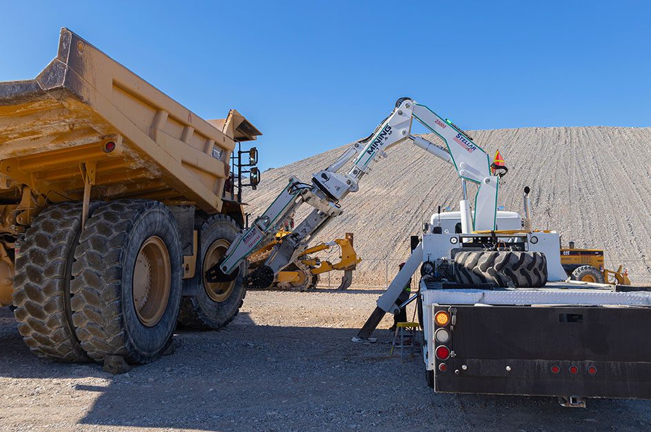 Stellar truck with mining attachment working on large mining truck